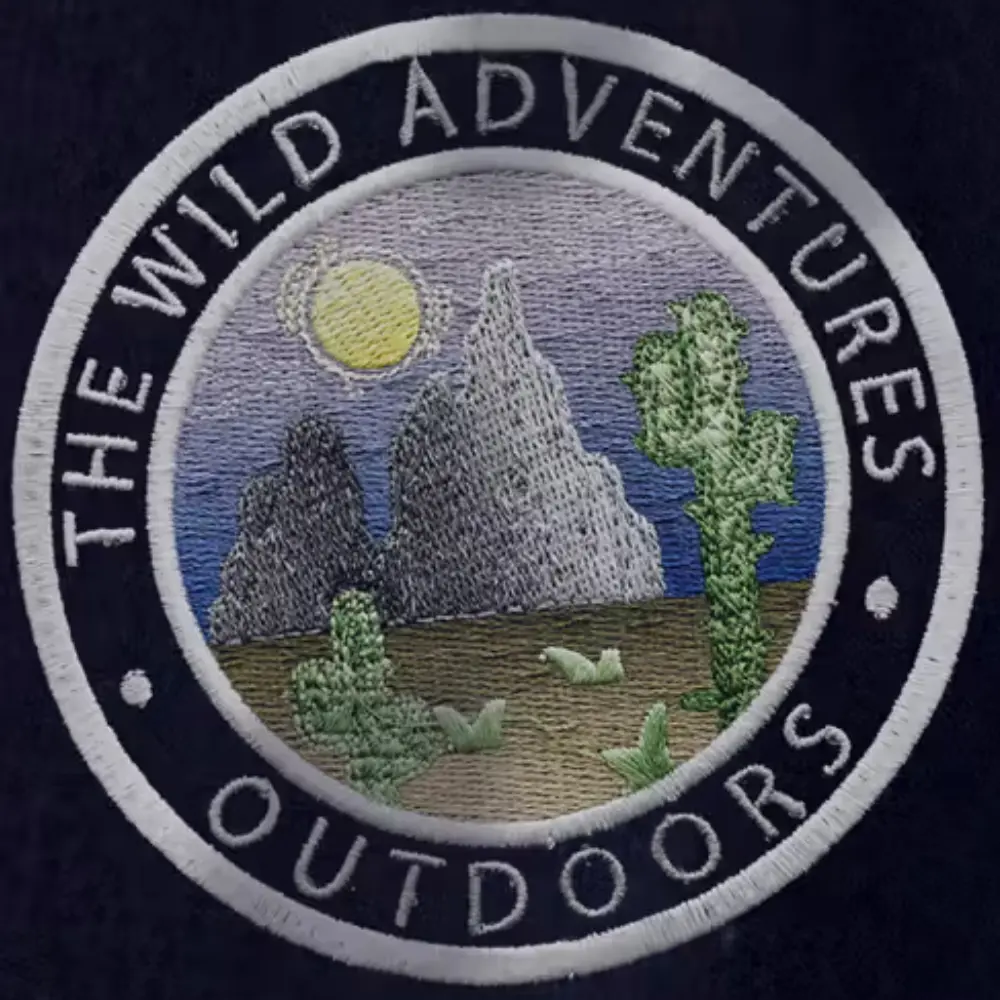 circular, embroidered patch features a desert scene with a mountain range under a yellow sun